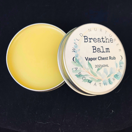 A small metal tin labeled "Breathe Rub: 2oz Chest & Head Vapor Rub | Upper Respiratory Ointment | Family Cold & Flu Support" by Wild Nurturer Aromatherapy on a white background.