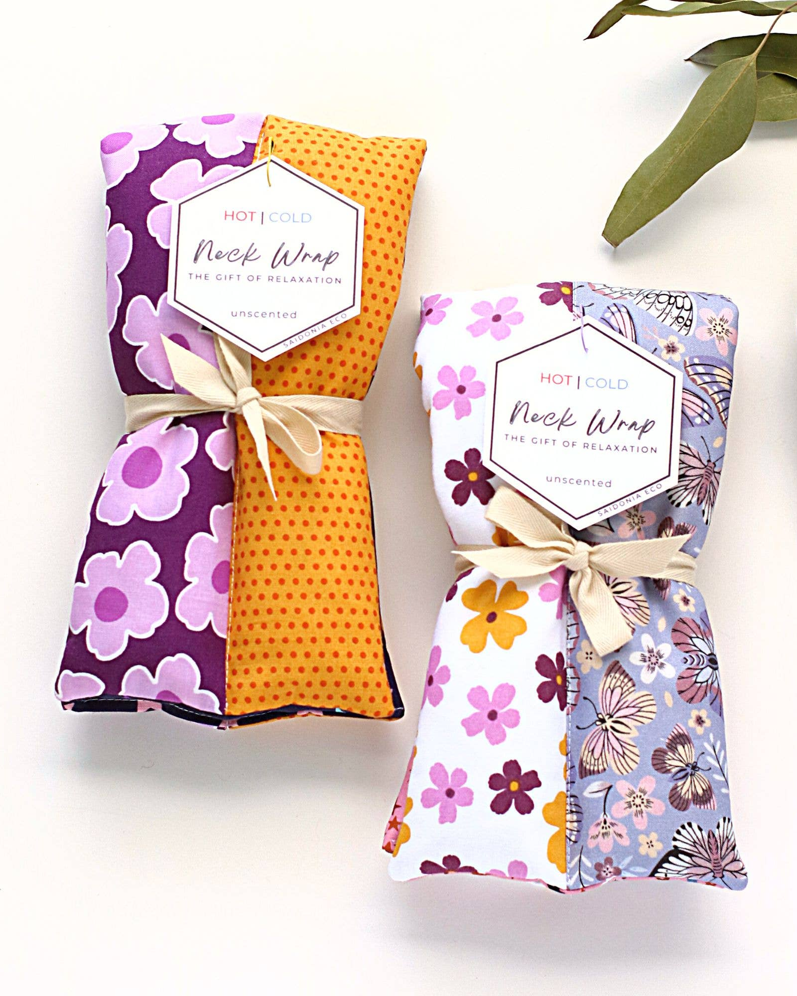 Three fabric hot/cold neck wraps with floral and polka dot designs, tied with ribbons and labeled, arranged on a white background.