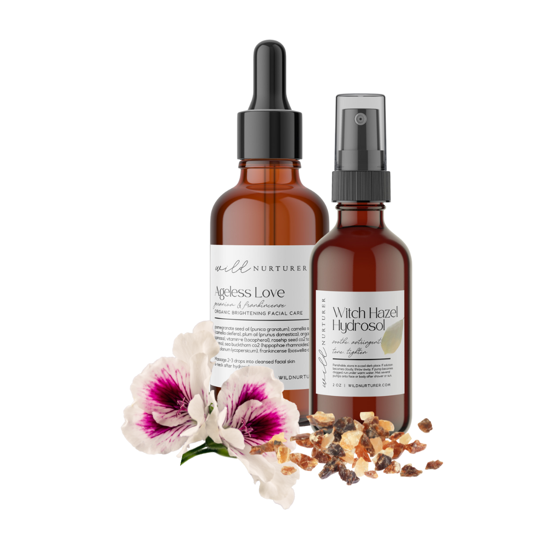 Two bottles of skincare oils labeled "Cuticle Oil" and "Face Love Oil" on a bathroom counter with decorative flowers in the background.