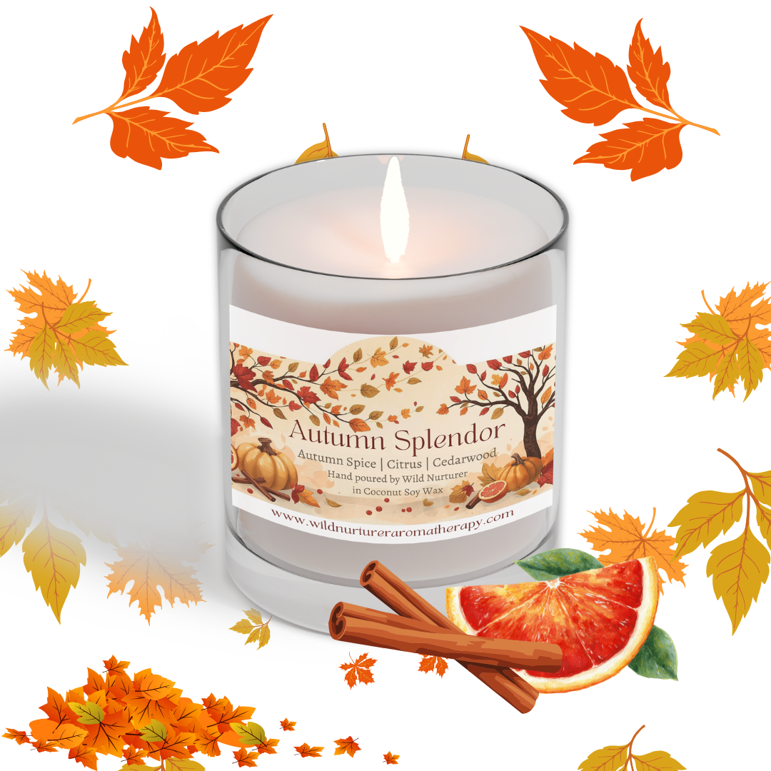 A lit Chai Latte Soy Candle from Wild Nurturer Aromatherapy sits surrounded by autumn leaves, a cinnamon stick, and an orange slice. The label highlights notes of vanilla, chai spice, and honey with a soy wax base—making this fall-scented candle the perfect way to bring cozy warmth into your home.