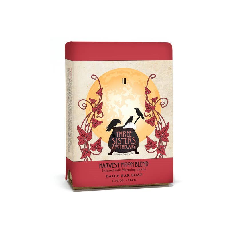 The Soap Cauldron's Bar Soap Harvest Moon packaging features autumnal leaves and two birds set against a prominent orange moon, enhanced with cleansing herbs for a captivating experience.