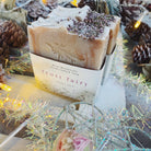 Handmade Bliss Botanicals Frost Fairy Soap displayed with pine cones and fairy lights on a rustic wooden surface.