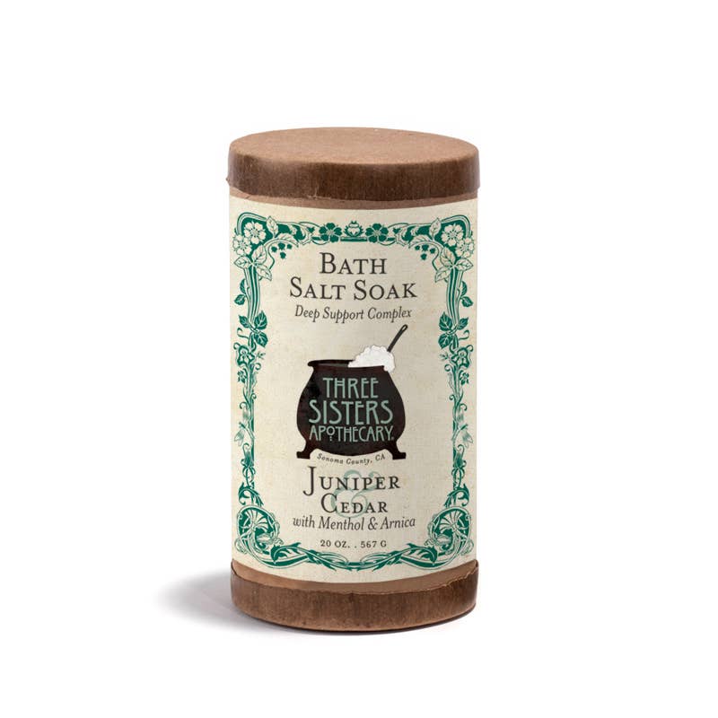 Cylindrical container of Soap Cauldron's Bath Salt Soak Juniper & Cedar: Large, featuring Epsom salts and a refreshing juniper cedar aroma, enhanced with menthol and arnica. Decorated with a vintage-style label.