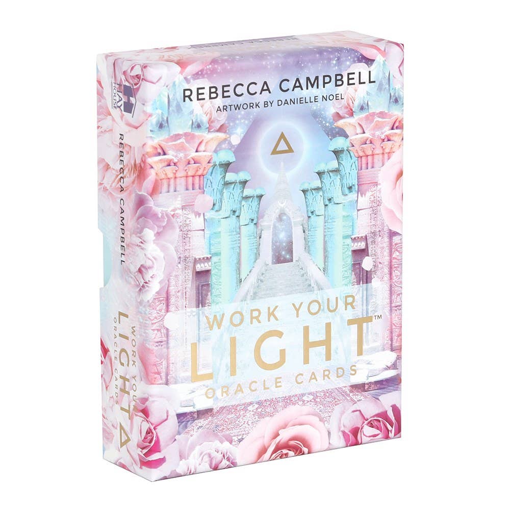 A box of the "Work Your Light Oracle Cards" by Something Different Wholesale, featuring artwork by Danielle Noel. This stunning 44-card deck showcases a mystical temple adorned with pink rose accents and a light blue color scheme, perfect for those seeking guidance and inspiration.